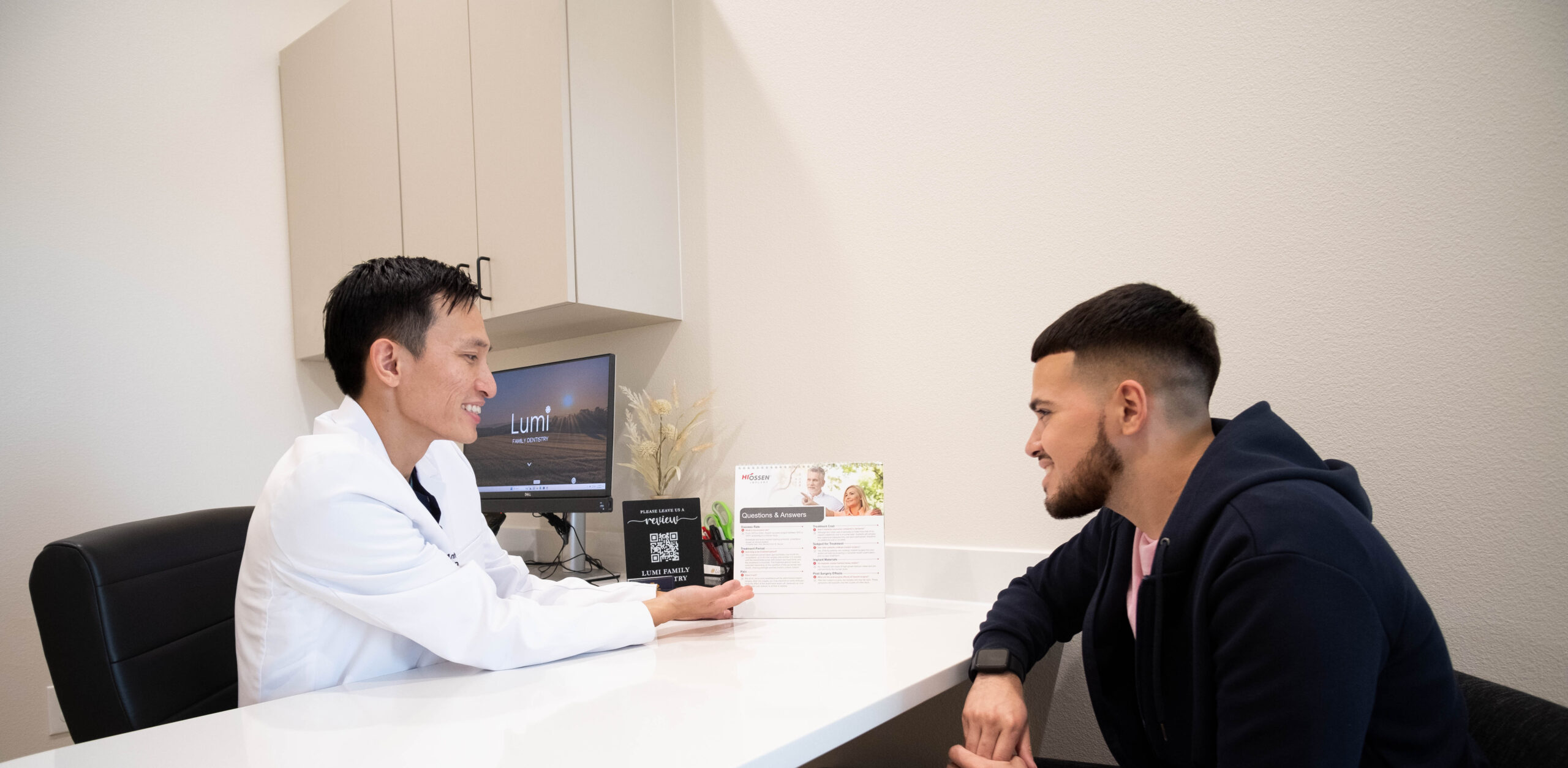 male doctor covering financial options with younger male patient at Lumi Dentistry